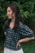 Shell button and loop detail on gathered cotton blouse, close-up