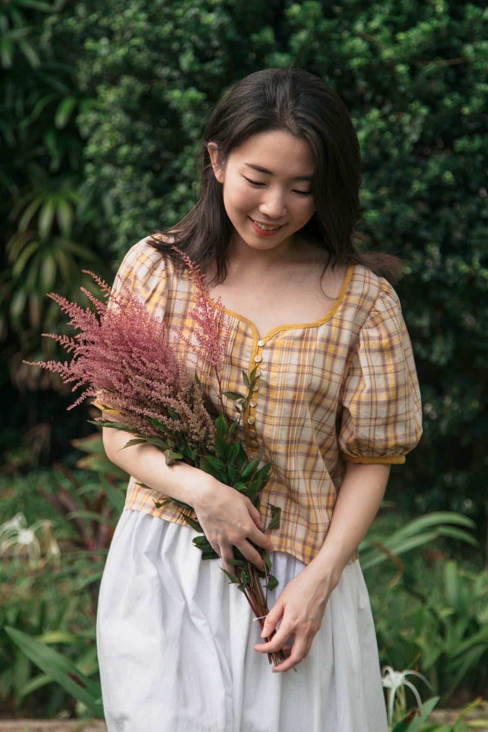 Woman holding a bouquet of flowers in a garden setting